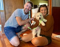 a man and woman posing for a photo with a puppy